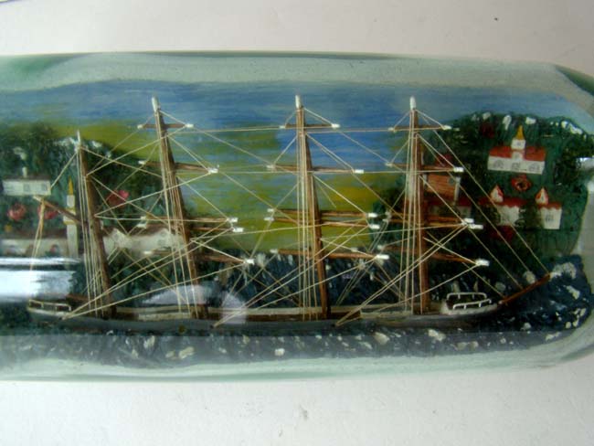 A four masted ship in a bottle flying an American flag with an American coastal town in the background. Circa 1930-1940 — image 3